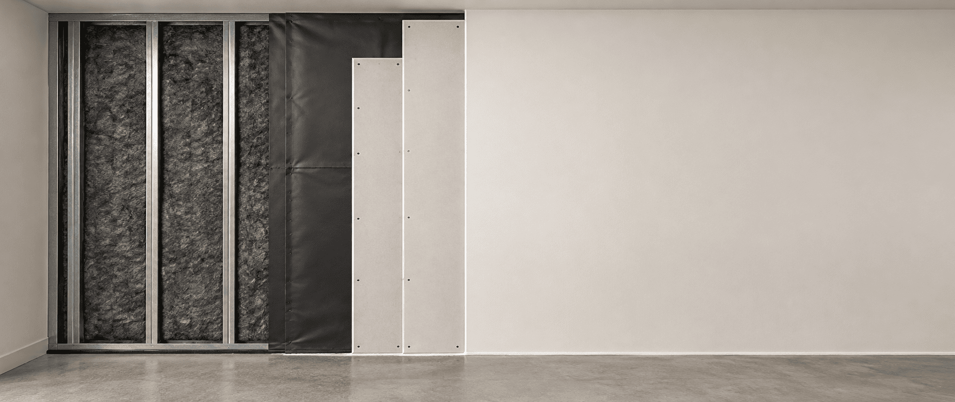 Partition wall under construction showing a dense barrier membrane behind the gypsum board layer
